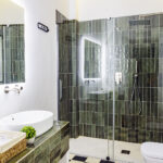 Cuarto de baño de diseño en planta segunda de NintaiHome, con acabados en verde y equipamiento de alta calidad.