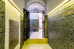 Entrada histórica con azulejos tradicionales en NintaiHome Los Venerables, un reflejo del encanto auténtico de Sevilla en el barrio de Santa Cruz.