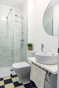 Interior de baño de diseño con acabados modernos y espejo redondo en NintaiHome Los Venerables.