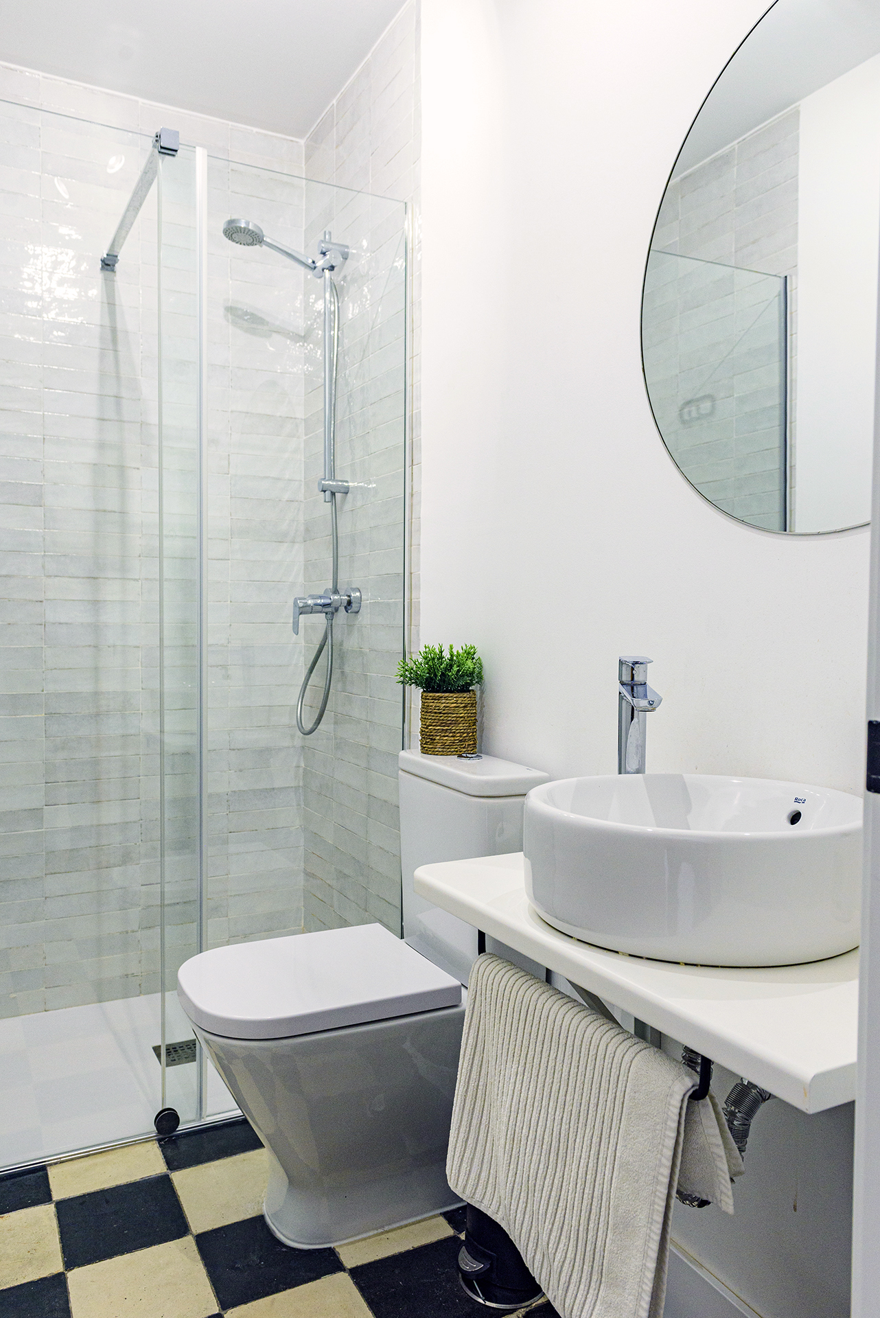 Interior de baño de diseño con acabados modernos y espejo redondo en NintaiHome Los Venerables.