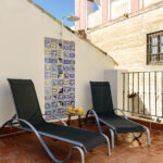 Terraza solárium en NintaiHome, Sevilla, con tumbonas y ducha exterior decorada con azulejos típicos, situada junto al histórico Hospital de los Venerables.