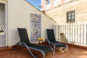 Terraza solárium en NintaiHome, Sevilla, con tumbonas y ducha exterior decorada con azulejos típicos, situada junto al histórico Hospital de los Venerables.
