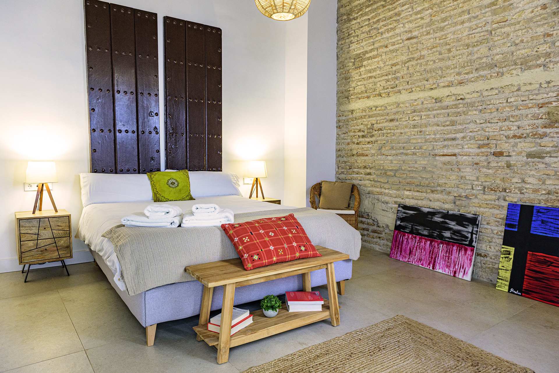 Dormitorio luminoso en la planta superior de NintaiHome en Sevilla, con una ventana-balcón que ofrece vistas a nuestro patio interior tradicional.