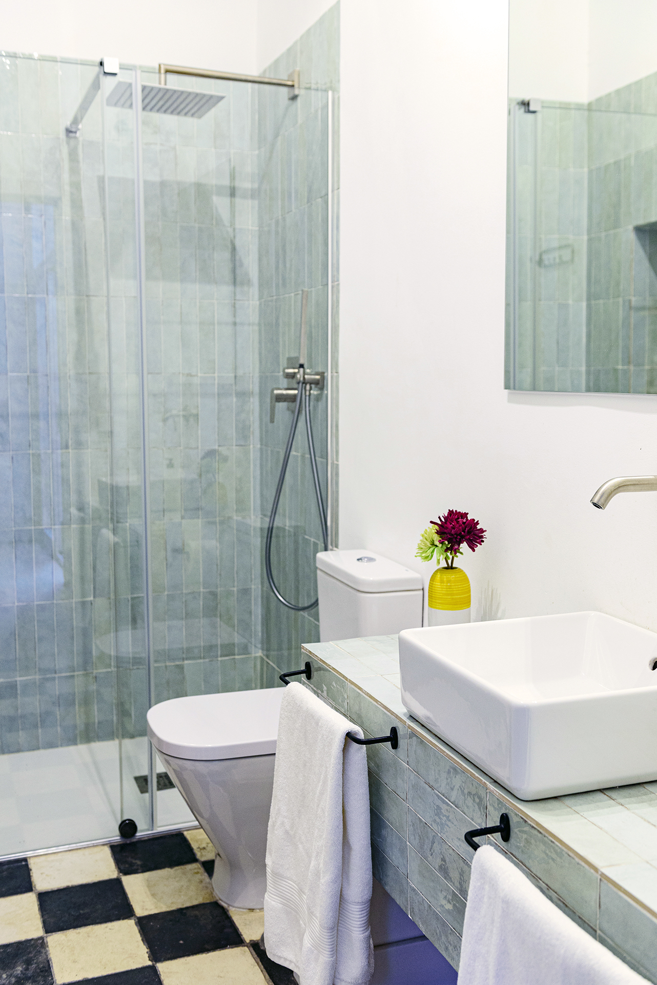 Interior de baño contemporáneo con lavabo cuadrado y ducha a ras de suelo, destacando la combinación de suelos clásicos y accesorios modernos en NintaiHome.