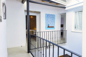 Pasillo luminoso en la segunda planta de NintaiHome Sevilla, con barandilla de hierro forjado y decoración de arte moderno.