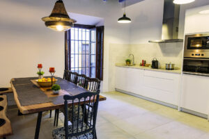 Cocina totalmente equipada y amplia mesa de madera en el comedor de NintaiHome Los Venerables, un espacio acogedor para compartir momentos inolvidables.